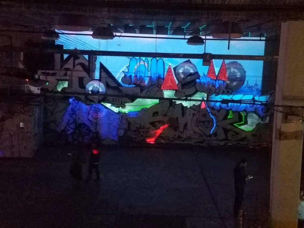The graffiti wall bathed in blue projection light at Nashville Night Market