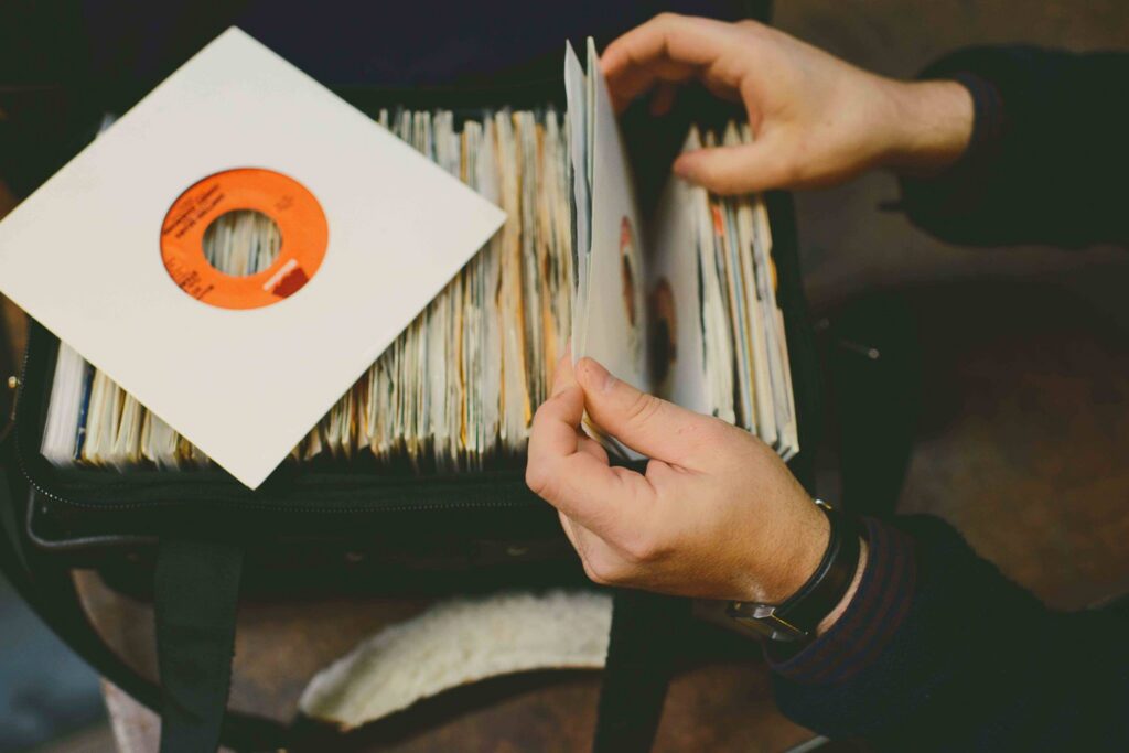 Hands flipping through vinyl 45s in a DJ record bag