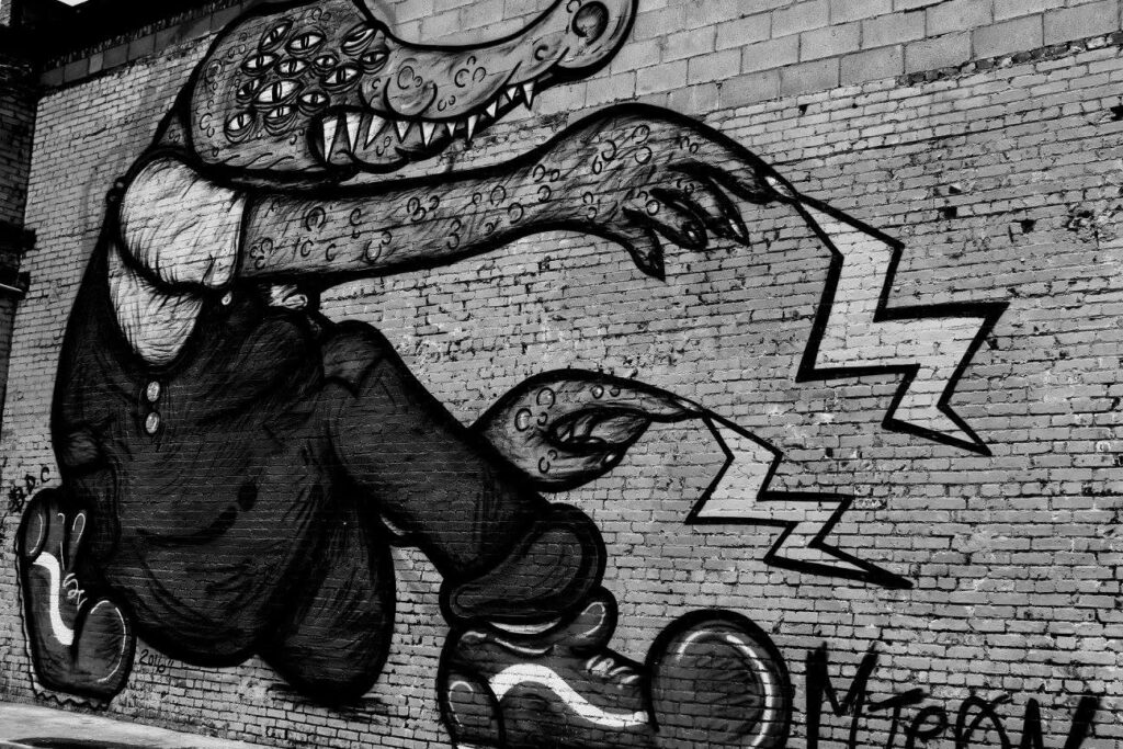 Black-and-white alligator mural painted on a brick wall, signed 2018