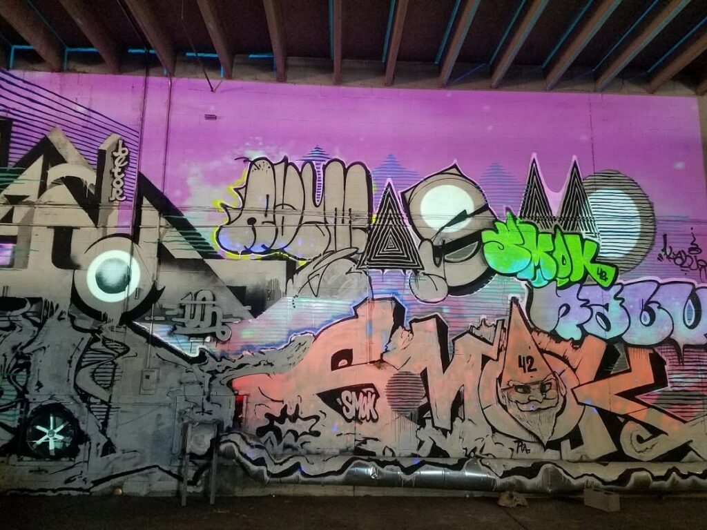 Graffiti-covered wall with colorful light projections at Bridge Below Space during Nashville Night Market