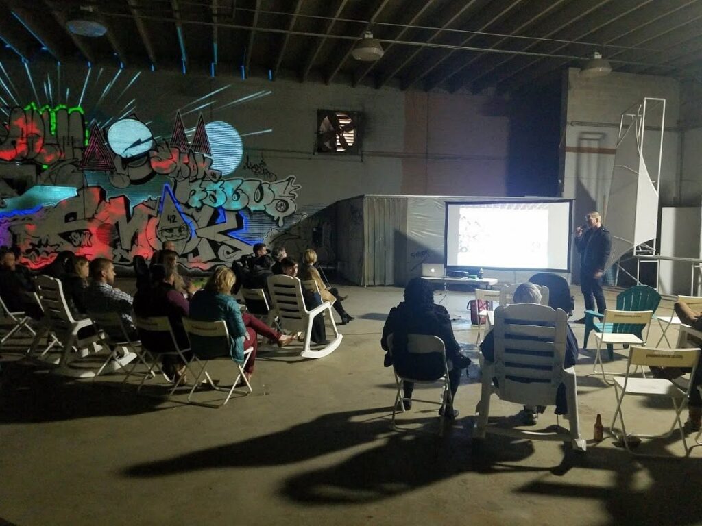 Attendees seated in chairs watching a presentation inside the Nashville Night Market warehouse venue