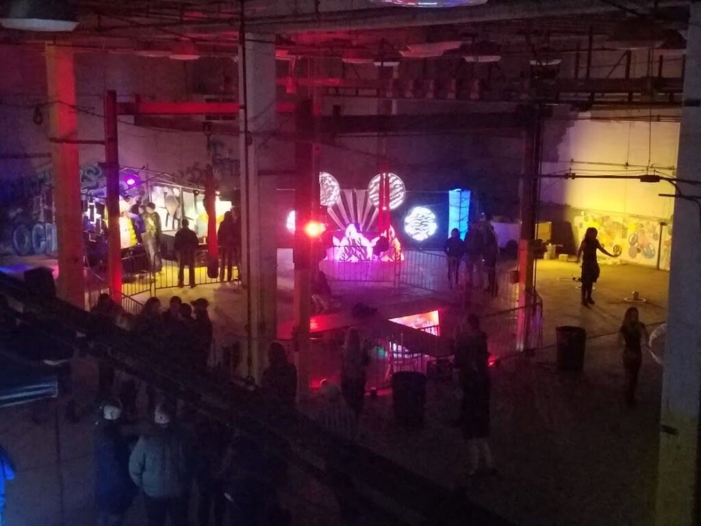 Crowd inside the warehouse venue at Nashville Night Market, with performers on a lit stage under red lights