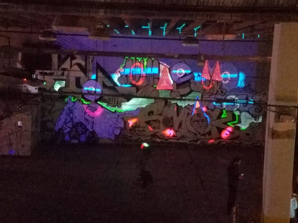 Wide view of the projection-mapped graffiti wall at Nashville Night Market with blue, green and red light art